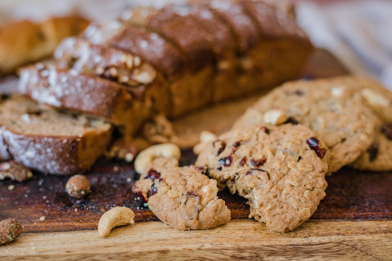 Close-up of sliced bread with nuts and delicious cookies on a rustic wooden board.